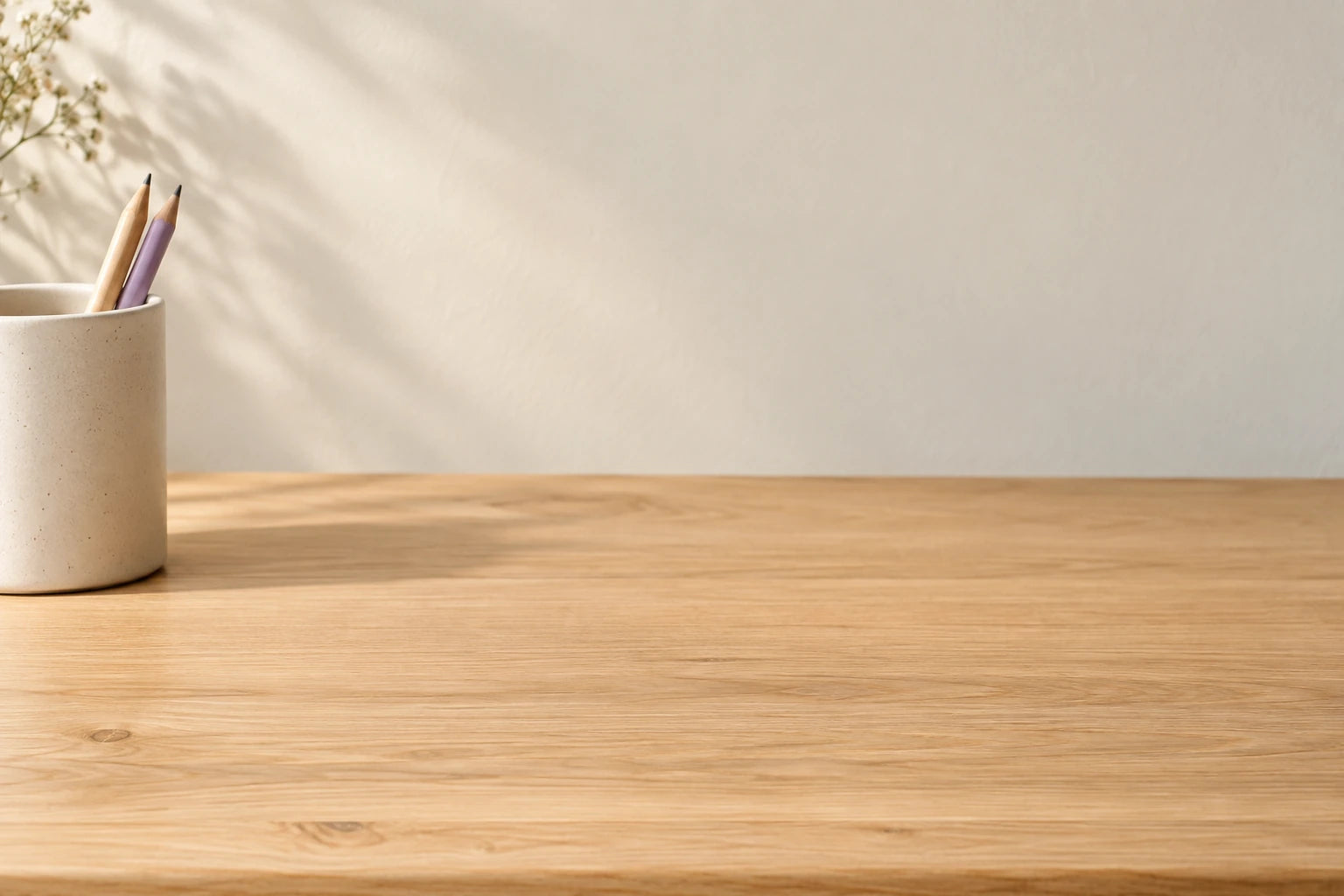 Close view of a warm oak desktop and ceramic pencil cup